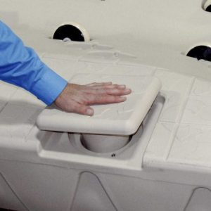 A person in a blue shirt places their hand on a Port Snap-in Cap on a beige textured surface.