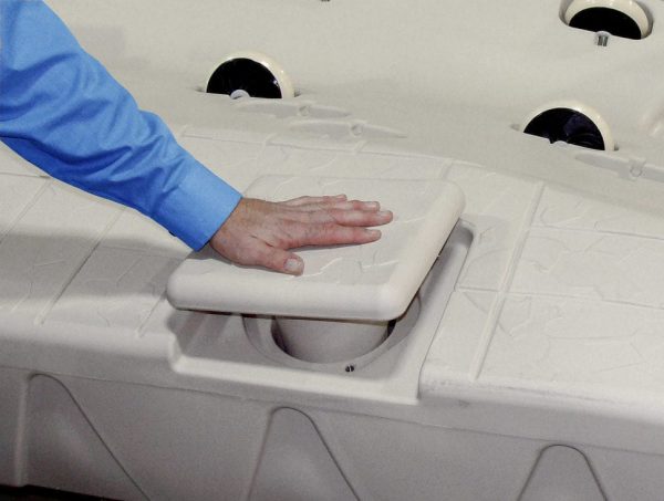 A person in a blue shirt places their hand on a Port Snap-in Cap on a beige textured surface.